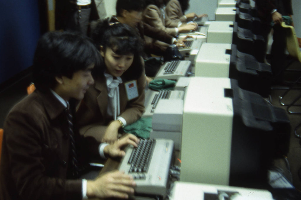 This is a photograph of Taiwanese dancers spending time at computers outside of their performance activities.